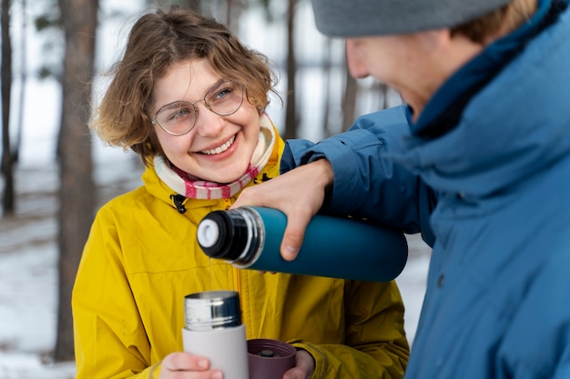 Amigos disfrutando de una bebida caliente durante un viaje de invierno