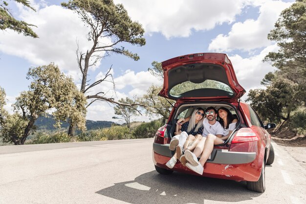 Amigos disfrutando en el maletero del coche en la carretera