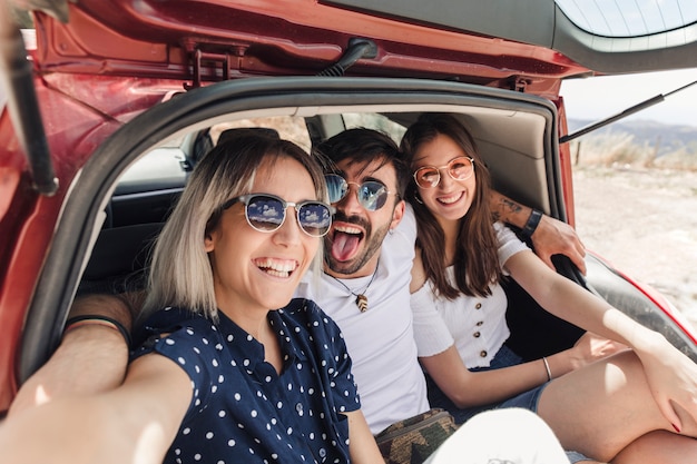 Foto gratuita amigos disfrutando en el maletero del coche