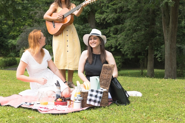 Amigos disfrutando de la música de picnic en el parque.