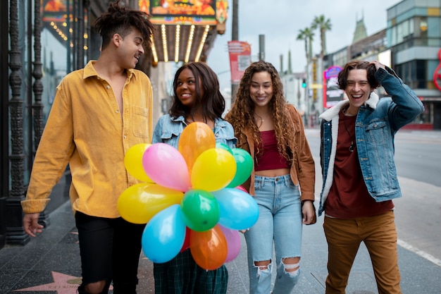 Foto gratuita amigos divirtiéndose con globos mientras están en la ciudad.