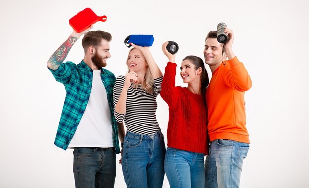 Amigos divirtiéndose juntos sonriendo escuchando música en altavoces inalámbricos, bailando riendo aislado en blanco