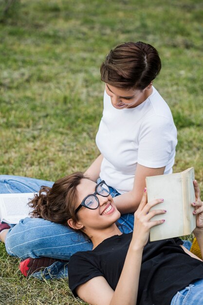 Amigos divirtiéndose en el parque leyendo libros