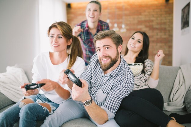 Amigos expresivos jugando al juego en el sofá