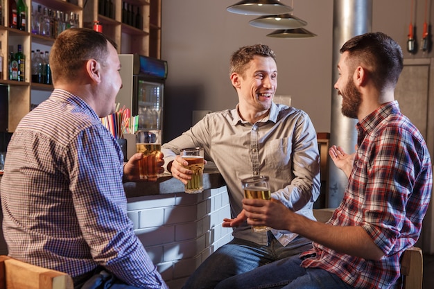 Foto gratuita amigos felices bebiendo cerveza en el mostrador en pub