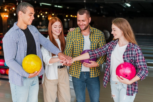 Amigos felices con coloridas bolas de boliche en un club de bolos