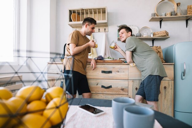 Amigos felices disfrutando de beber jugo en la cocina