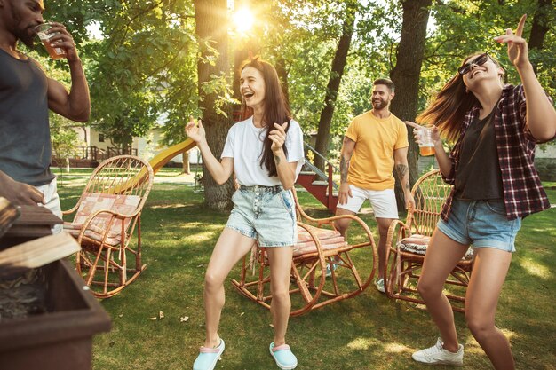 Amigos felices están tomando cerveza y fiesta de barbacoa en un día soleado