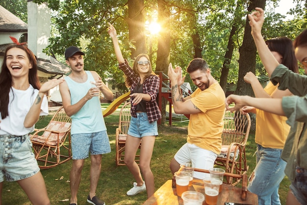 Amigos felices están tomando cerveza y fiesta de barbacoa en un día soleado