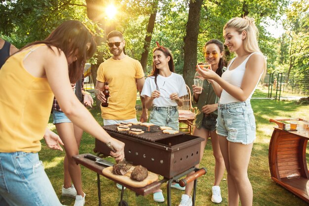 Amigos felices están tomando cerveza y fiesta de barbacoa en un día soleado