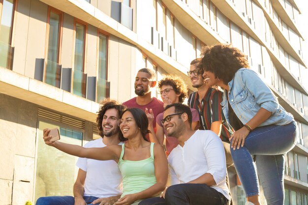 Amigos felices felices multiétnicas que toman selfie grupal