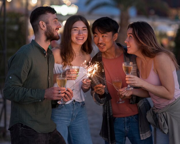 Amigos felices de fiesta con fuegos artificiales