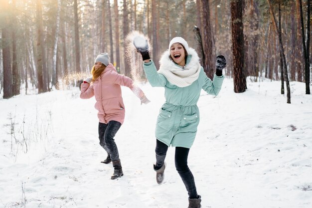 Amigos felices jugando con nieve al aire libre en invierno