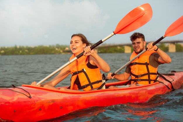 Amigos felices en kayak en el río con puesta de sol