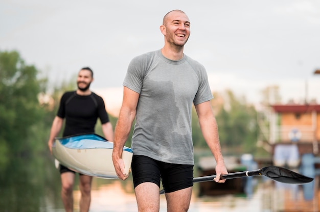 Amigos felices llevando una canoa