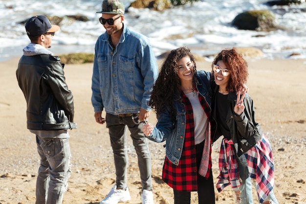 Foto gratuita amigos felices de las mujeres africanas caminando al aire libre en la playa.