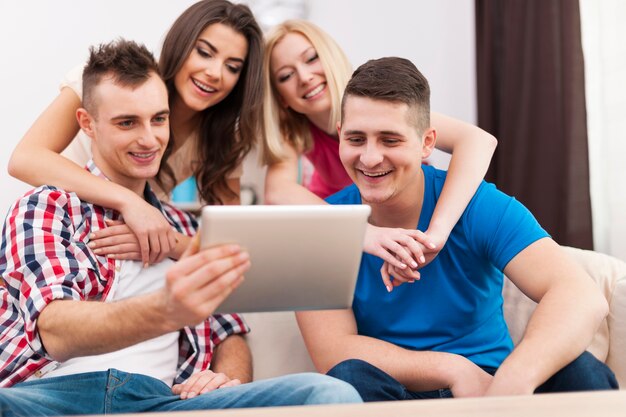 Amigos felices pasando tiempo libre y usando tableta digital en casa