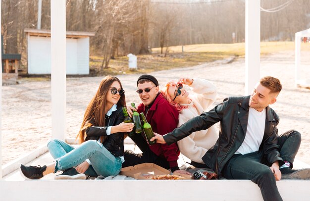 Amigos felices en picnic tintineando cerveza