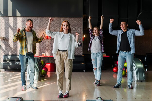 Amigos felices de pie en un club de bolos