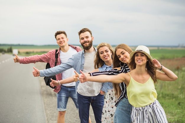 Foto gratuita amigos felices de pie en fila en el camino de autostop