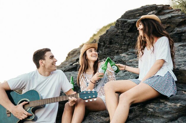 Amigos felices en la playa con guitara