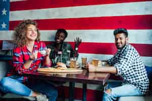 Foto gratuita amigos felices que descansan juntos en el bar, mujeres y hombres en el café, hablando, riendo comen comida rápida.