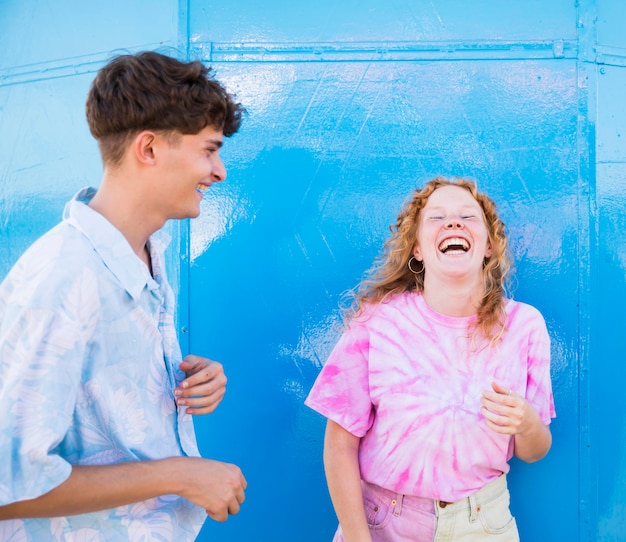 Amigos felices riendo con pared azul detrás