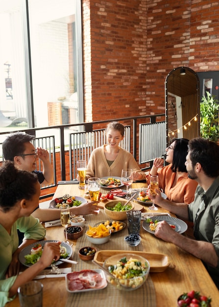 Foto gratuita amigos felices sentados en la mesa