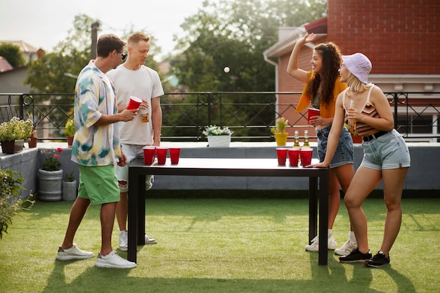 Amigos felices de tiro completo jugando al pong de la cerveza