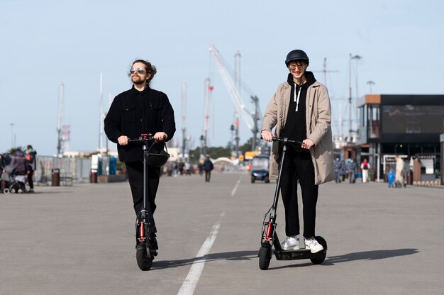 Amigos felices de tiro completo con scooters eléctricos