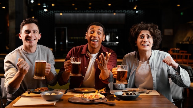 Amigos felices de tiro medio con cerveza en el pub