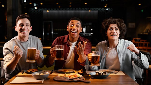 Amigos felices de tiro medio con cerveza en el pub