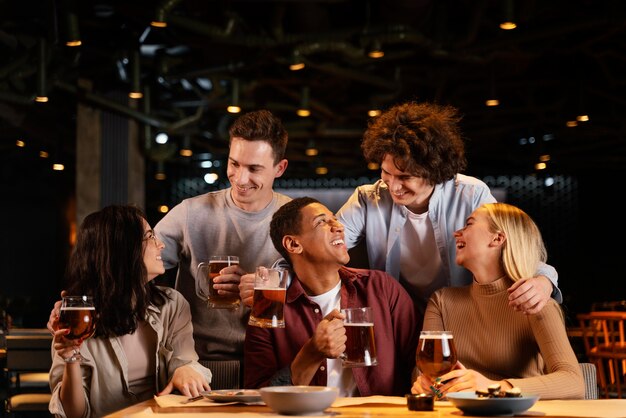 Amigos felices de tiro medio sentado en el pub