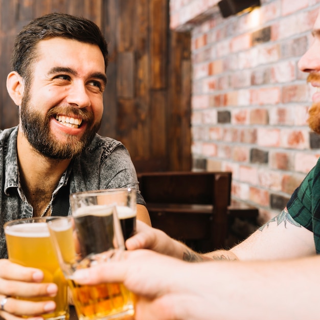 Amigos felices tostado copas de bebidas alcohólicas en el bar