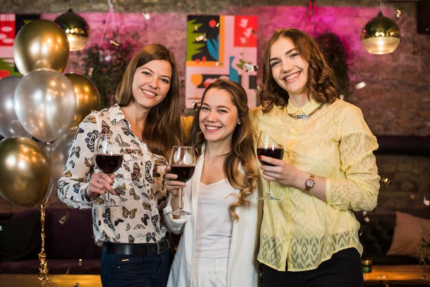 Amigos femeninos jovenes sonrientes en barra que disfrutan de bebidas