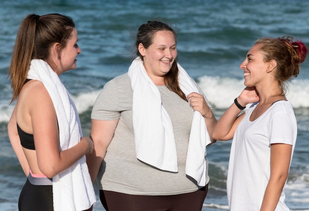 Foto gratuita amigos de fitness de tiro medio en la playa