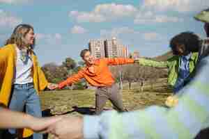 Foto gratuita amigos girando y tomados de la mano en un campo al aire libre