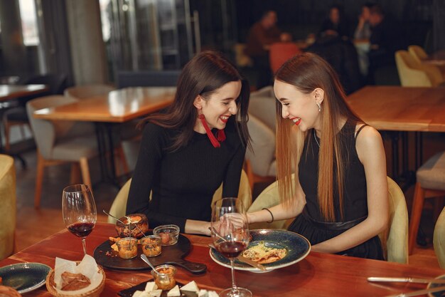 Amigos hablando y divirtiéndose en la cena. Mujeres elegantemente vestidas de personas cenando.