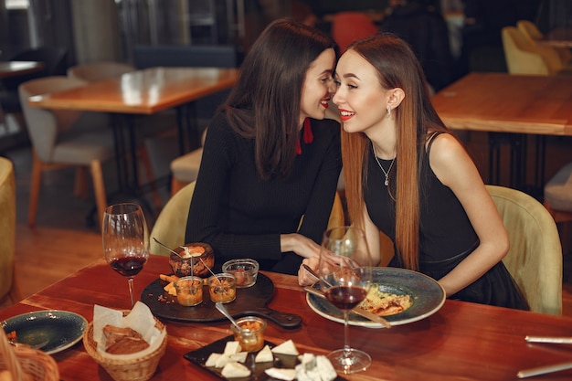 Foto gratuita amigos hablando y divirtiéndose en la cena. mujeres elegantemente vestidas de personas cenando.