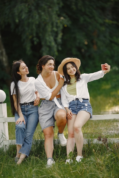 Los amigos se hacen una selfie. Chica con sombrero. Mujer con camiseta blanca.