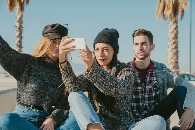 Amigos haciendo selfie enfrente de palmera