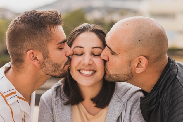 Amigos hombres besando a mujer