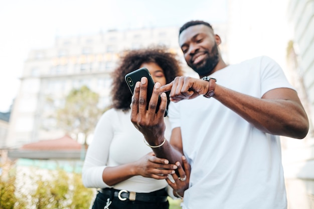 Amigos interculturales afuera mirando el teléfono