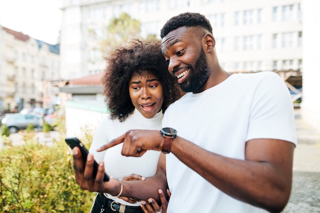 Foto gratuita amigos interculturales apuntando por teléfono