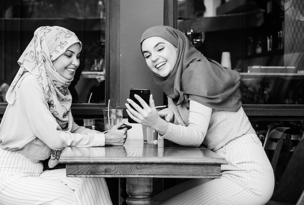 Amigos islámicos hablando y mirando en el teléfono inteligente