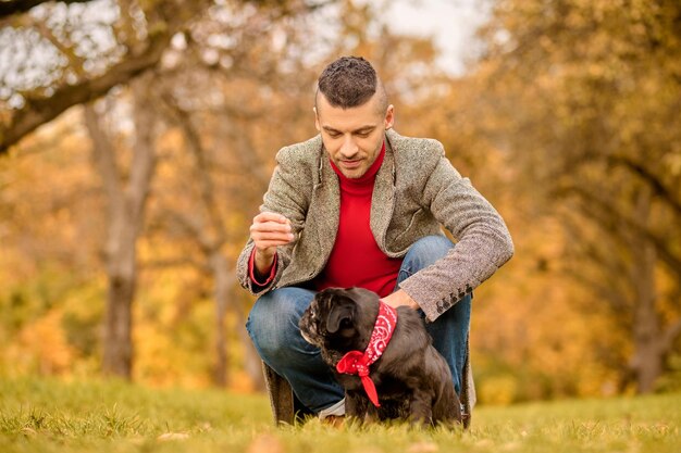 Amigos. Un joven con su mascota en el parque de otoño.