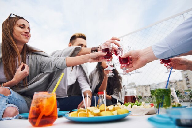 Amigos jóvenes felices estaban sentados en una mesa y haciendo un picnic al aire libre.