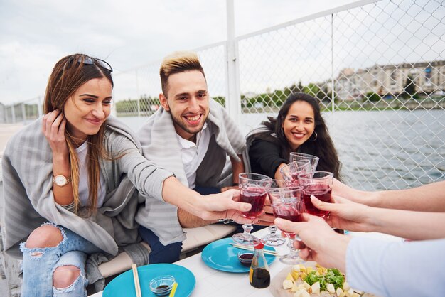 Amigos jóvenes felices estaban sentados en una mesa y haciendo un picnic al aire libre.