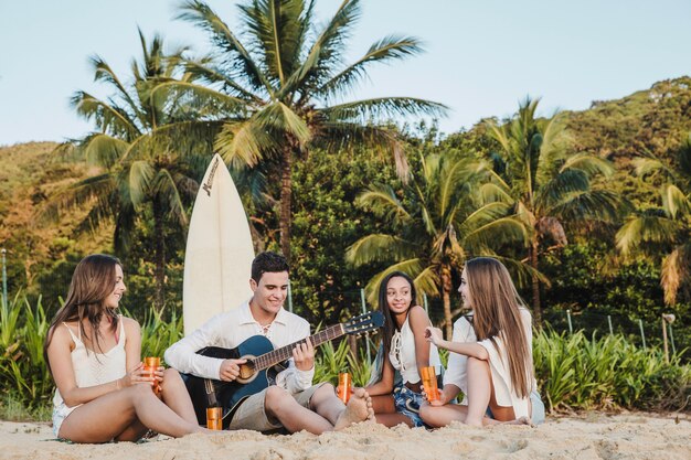 Amigos jóvenes tocando la guitarra en la playa