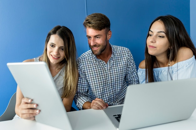 Amigos jóvenes trabajando con dispositivos